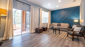Un salon moderne avec un canapé, des fauteuils, une table basse et un tapis à motifs.