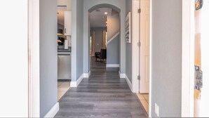 Un couloir doté d’un plancher en bois foncé, de moulures blanches et de murs gris clair.