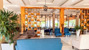 A spacious lobby with a blue sofa, wooden shelving, and potted plants. - Mozza Beach Resort (York)