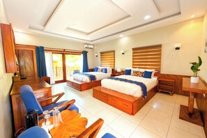 A hotel room with two beds, a desk, a chair, and a dining table.