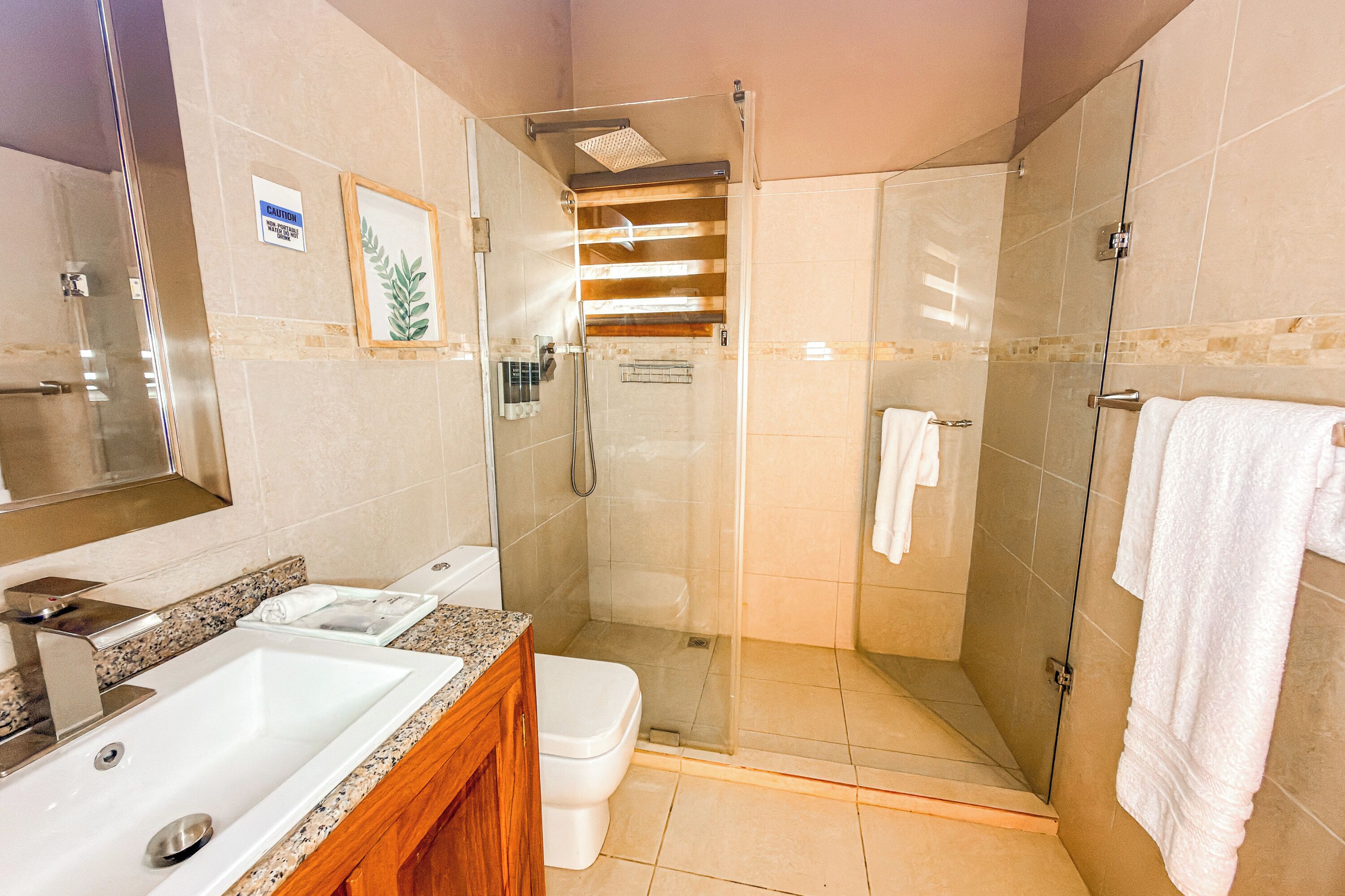 Een badkamer met een glazen douchecabine, een wastafel en een toilet.