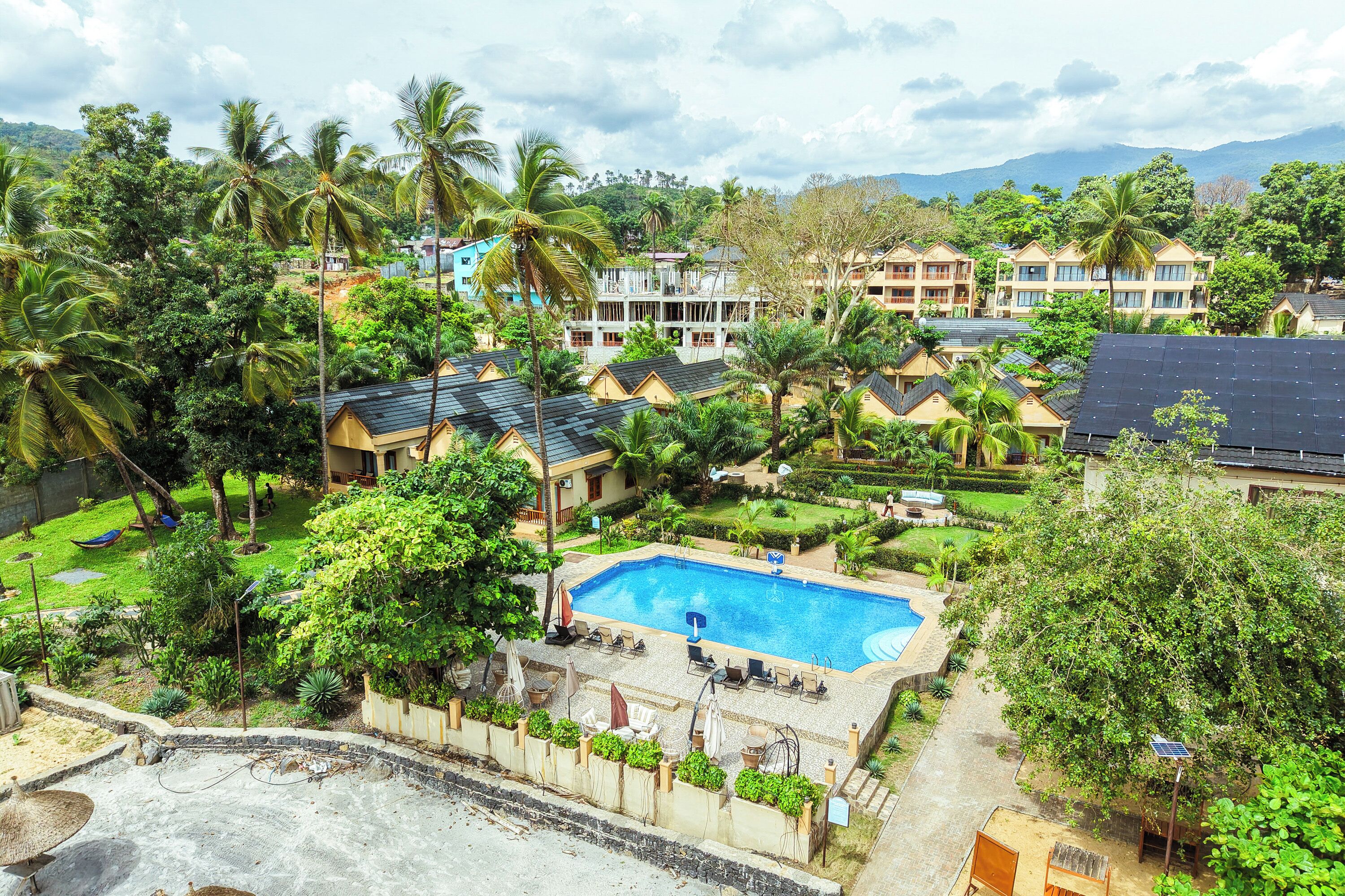 A resort with a swimming pool, palm trees, and multiple buildings.