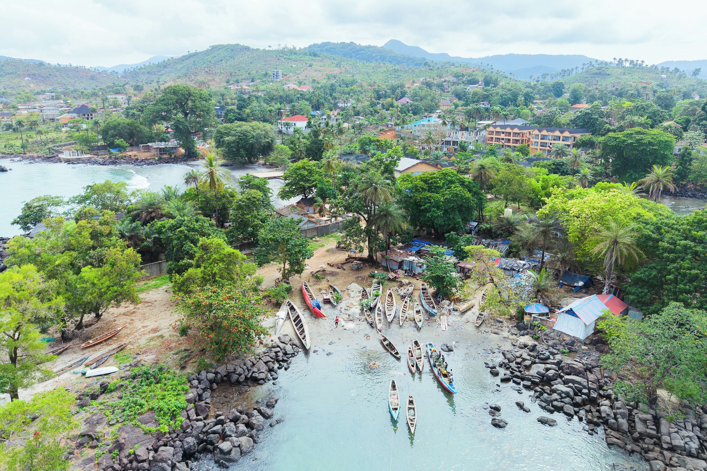 A coastal village with boats, houses, and a mountainous backdrop.