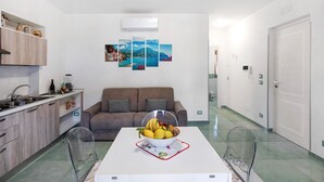 A modern kitchen with a dining table, a sofa, and a clear glass chair. - Apartment 'La Dimora Dei Nonni' with Mountain View, Wi-Fi and Air Conditioning (Agerola)