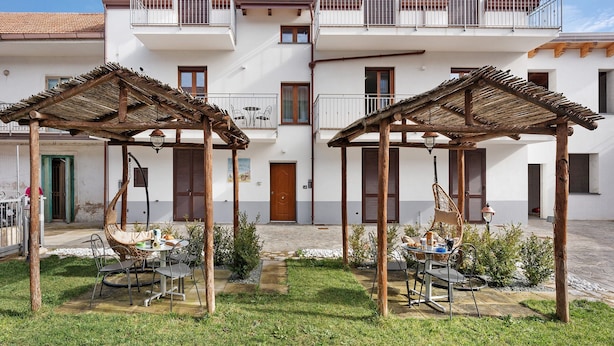 A two-story building with a courtyard, outdoor seating, and a wooden pergola. - Apartment 'La Dimora Dei Nonni' with Mountain View, Wi-Fi and Air Conditioning (Agerola)