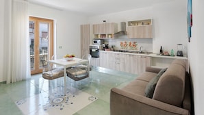 A modern kitchen with a dining area, a sofa, and a sliding glass door leading to a balcony. - Apartment 'La Dimora Dei Nonni' with Mountain View, Wi-Fi and Air Conditioning (Agerola)