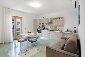 Una cocina moderna con comedor, sofá y puerta corrediza de vidrio que da a un balcón.