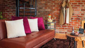 Een moderne woonkamer met een bruine leren bank, een houten salontafel en een bakstenen muur.