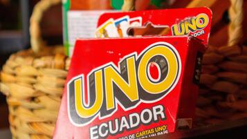 A Uno Ecuador card game box on a table with a woven basket and a can of beverage in the background.