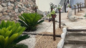 Un muro de piedra, una escalera y plantas en macetas en un jardín.