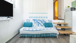 Un dormitorio con cama, televisor, microondas y una pequeña mesa.