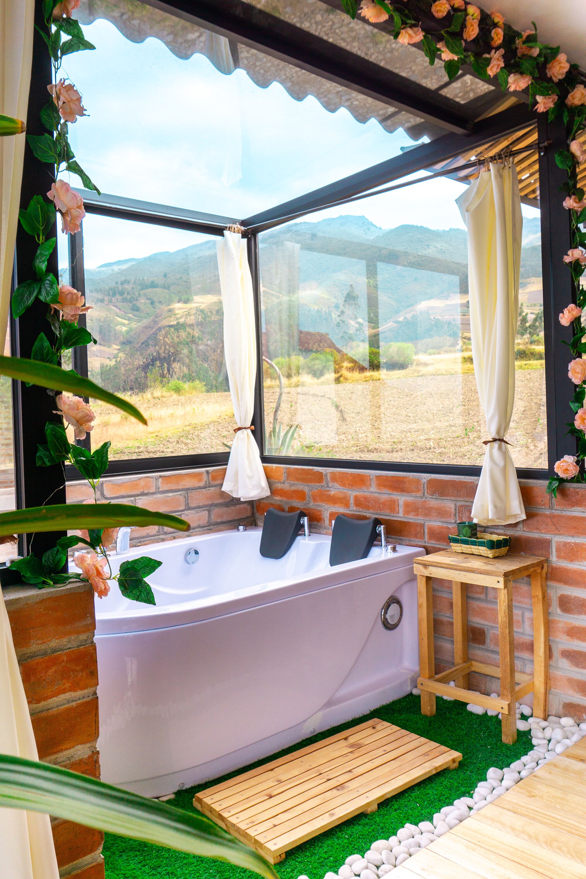 Ein Wellnessbereich mit Badewanne, Holzschemel und Blick ins Grüne.