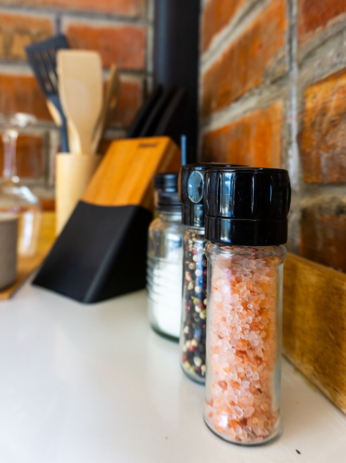 A kitchen counter with salt and pepper shakers, a wooden cutting board, and a knife block.