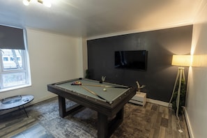 A pool table with balls, a television mounted on the wall, and a lamp. - Housesleep14-freep-garden-bbq-patio-pooltable (London)