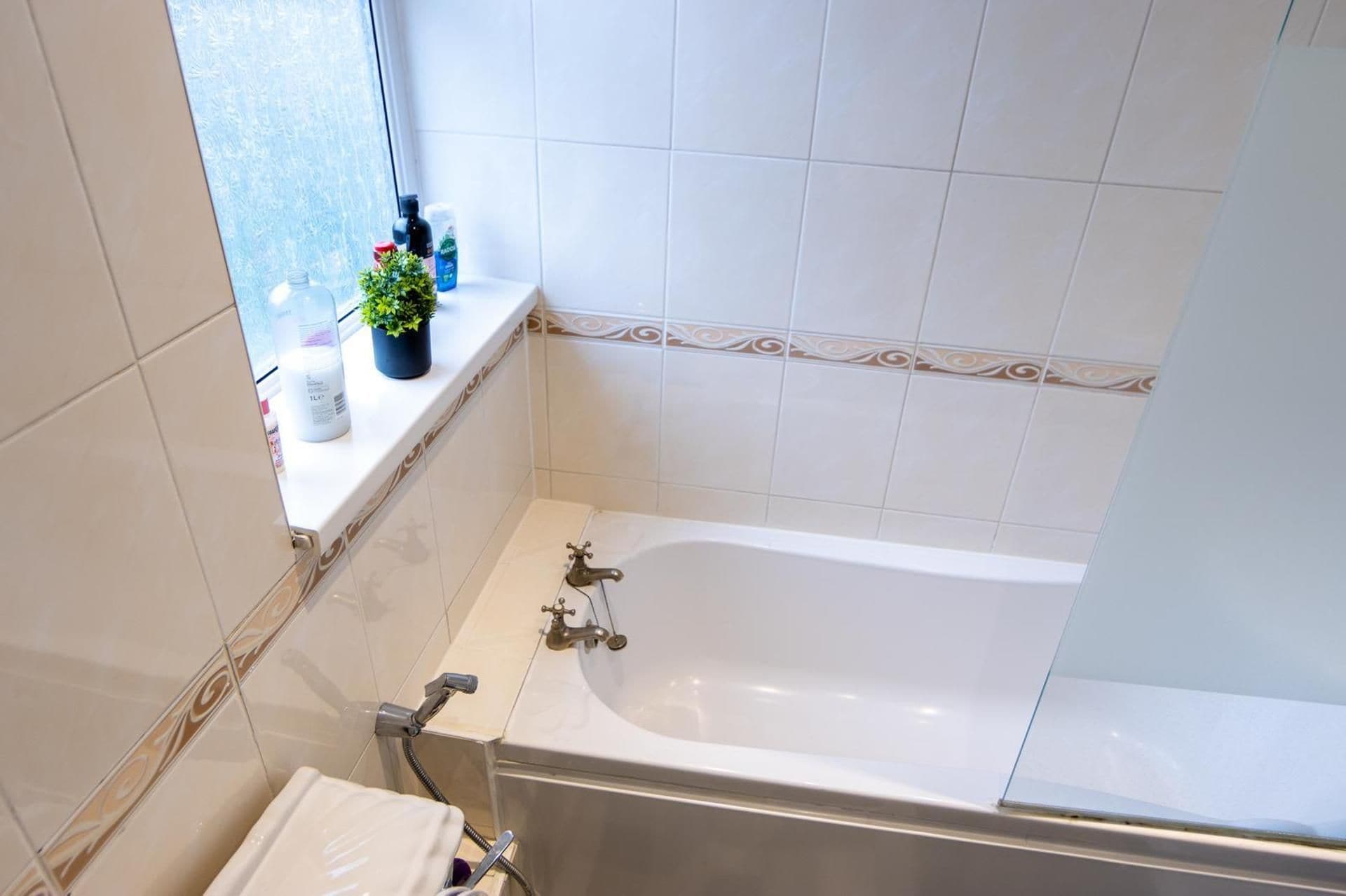 A bathroom with a bathtub, a toilet, and a window with a view.