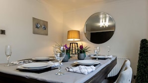 Un coin repas avec une table dressée pour deux personnes, une lampe et un miroir au mur.