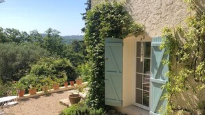 A rustic building with a gravel patio, potted plants, and a wooden table. - Beautiful ground floor apartment in villa in Opio. (Opio)