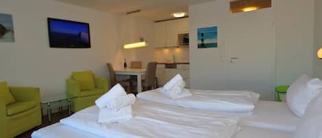 A hotel room with two beds, a dining area, and a kitchenette.
