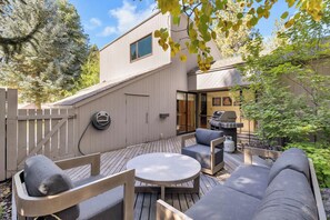 An outdoor patio with a round table, two sofas, and a grill.