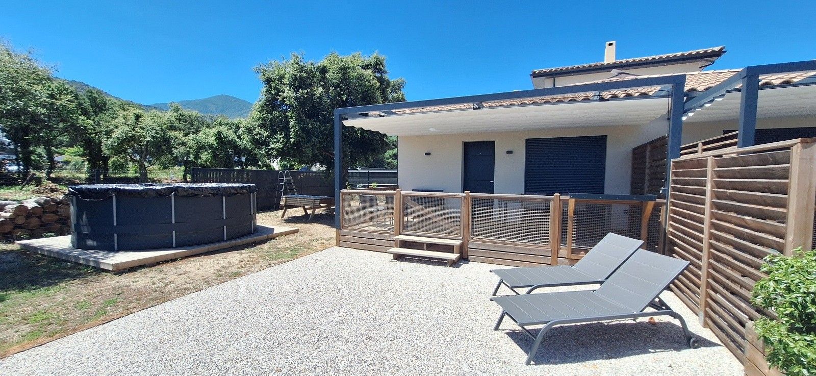 Un espacio exterior cubierto con piscina, sillas de descanso y bañera de hidromasaje.