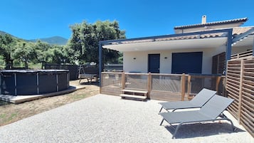 Un espacio exterior cubierto con piscina, sillas de descanso y bañera de hidromasaje.