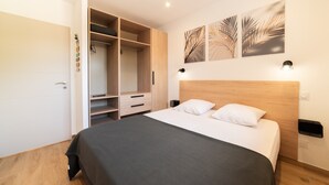 A bedroom with a bed, a wardrobe, and two wall-mounted light fixtures. - Charming 'Côté Nature' Cottage with Mountain View, Wi-Fi & Air Conditioning (Sorède)