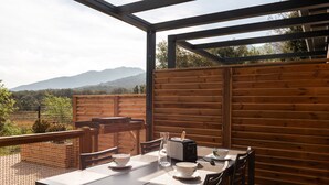 An outdoor dining area with a table set for two, a coffee maker, and a view of the mountains. - Charming 'Côté Nature' Cottage with Mountain View, Wi-Fi & Air Conditioning (Sorède)