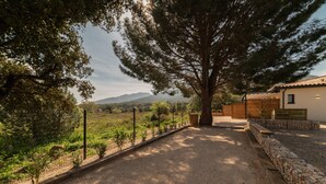 A gravel pathway leading to a building with a tiled roof, surrounded by trees and a fenced garden. - Charming 'Côté Nature' Cottage with Mountain View, Wi-Fi & Air Conditioning (Sorède)