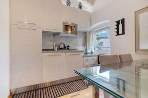 A modern kitchen with a glass dining table, stainless steel appliances, and a view of the outdoors. - White Residence: central Riva del Garda, private parking and modern design (Riva del Garda)