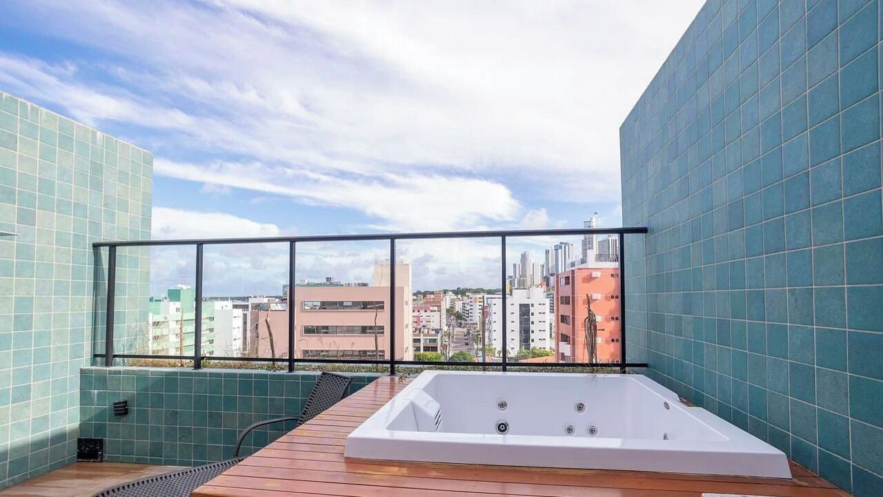 A rooftop terrace with a white hot tub, a wooden deck, and a city view.