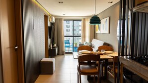 A modern kitchen with a dining area, a view of the city through large windows, and a kitchenette. - Oceânica Cabo Branco By Carpediem (João Pessoa)