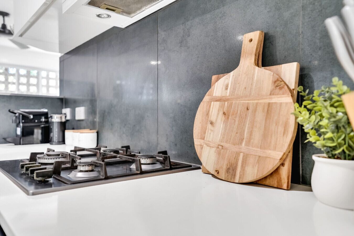 Une cuisine moderne équipée d’une cuisinière à gaz, d’une planche à découper en bois et d’une plante en pot.