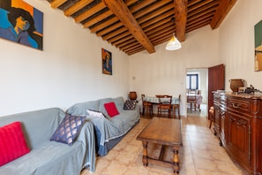 A living room with a sofa, a wooden table, and a dining area with chairs and a table. - Holiday Home 'La Clavelle' with Mountain View, Private Terrace and Private Garden (Sanary-sur-Mer)