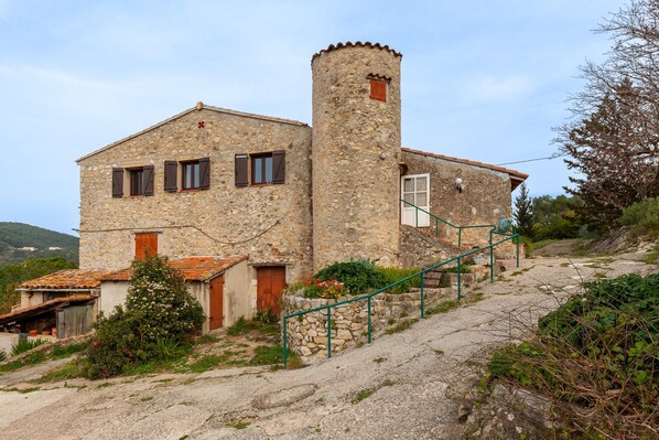 A stone building with a tower, a staircase, and a small garden.