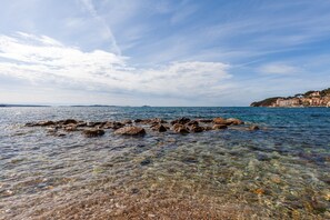 A coastal scene with clear water, rocks, and a distant shoreline with buildings. - Holiday Home 'La Clavelle' with Mountain View, Private Terrace and Private Garden (Sanary-sur-Mer)