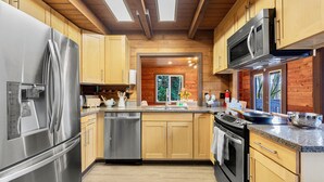 Une cuisine moderne dotée d’appareils électroménagers en acier inoxydable, d’armoires en bois et d’une lucarne.