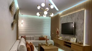Un salon moderne comprenant un canapé, une table basse, un téléviseur et des objets de décoration.