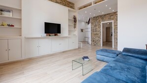 Un salon moderne avec un canapé bleu, une table basse en verre et un téléviseur à écran plat.