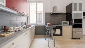 Une cuisine moderne avec des carreaux gris, des appareils électroménagers en acier inoxydable et une fenêtre.
