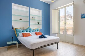 Quarto com cama, mesas de cabeceira, estante de vidro e vista pela porta.