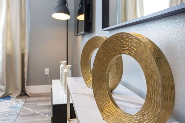 A modern interior with a marble countertop, two gold rings on the wall, and a black pendant light.