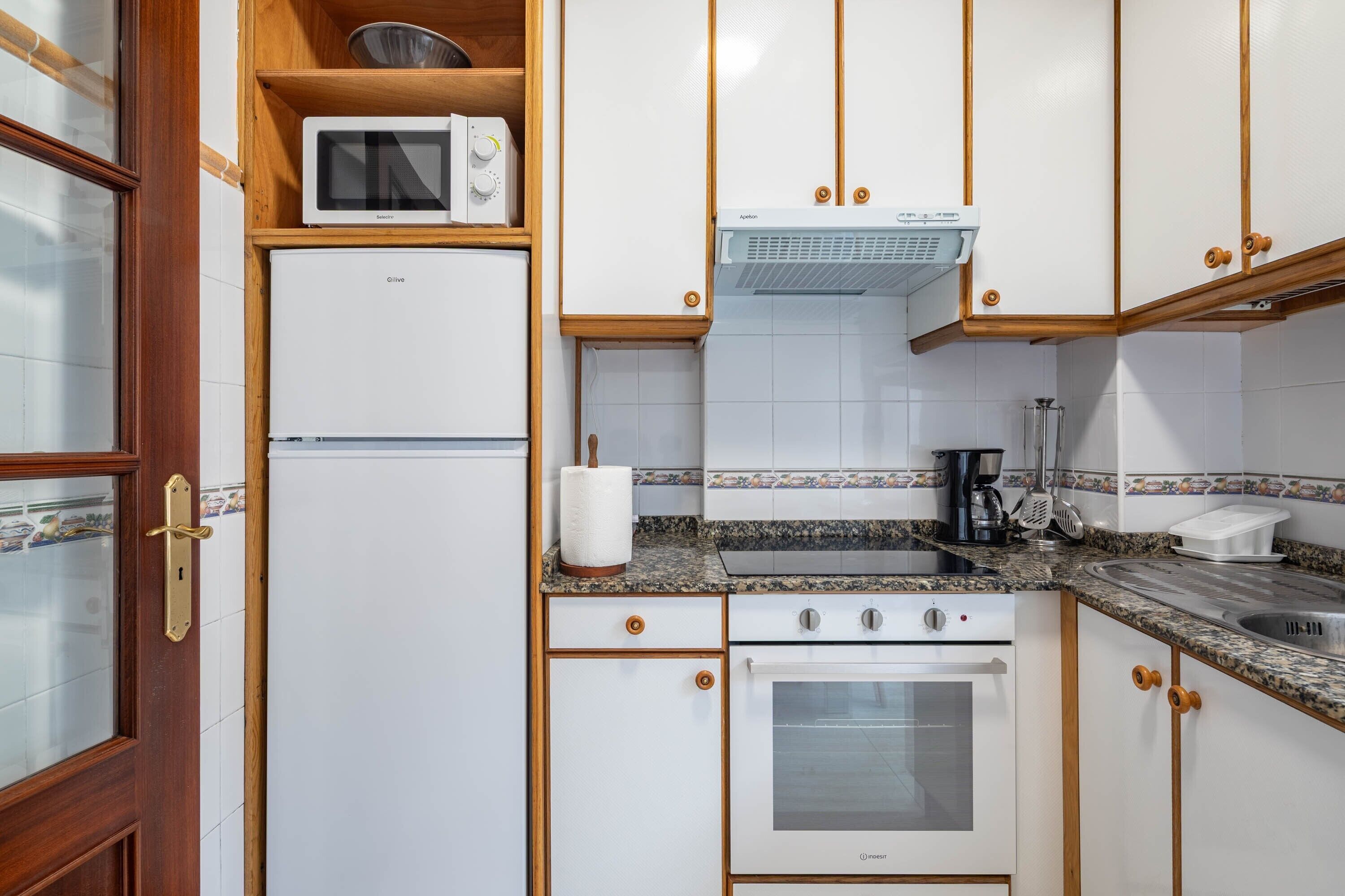 A kitchen with a refrigerator, microwave, stove, and oven.
