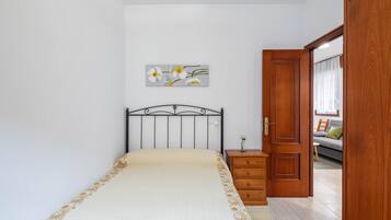 Un dormitorio con cama, mesita de noche, armario de madera y un cuadro en la pared.