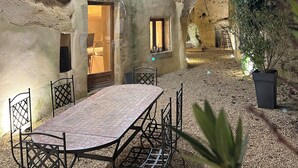 Un edificio rustico in pietra con una sala da pranzo, arredata con un tavolo e sedie, illuminata da luci a catena.
