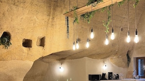 Un interno rustico con una parete in pietra, un tavolo da pranzo in legno e lampade a sospensione.