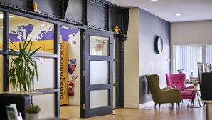 A modern office space with a large open door leading to a reception area, a world map on the wall, and a fire extinguisher mounted on the door. - Upperton Road Studios in Leicester (Leicester)