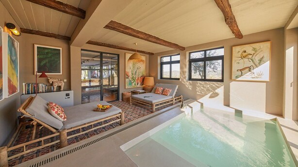 Un espace aménagé au bord de la piscine, avec deux chaises longues, une petite table sur laquelle sont disposés des fruits, et une vue sur la piscine.