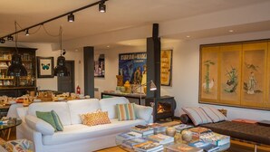 Un salon chaleureux avec un canapé blanc, une table basse sur laquelle sont posés des livres, une cheminée et une bibliothèque remplie de livres.