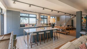 Une cuisine moderne dotée d’un îlot central, de tabourets de bar et d’un escalier menant à un niveau supérieur.