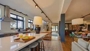 Une cuisine moderne dotée d’un grand îlot central, de tabourets de bar et d’un coin repas comprenant un canapé et une table.